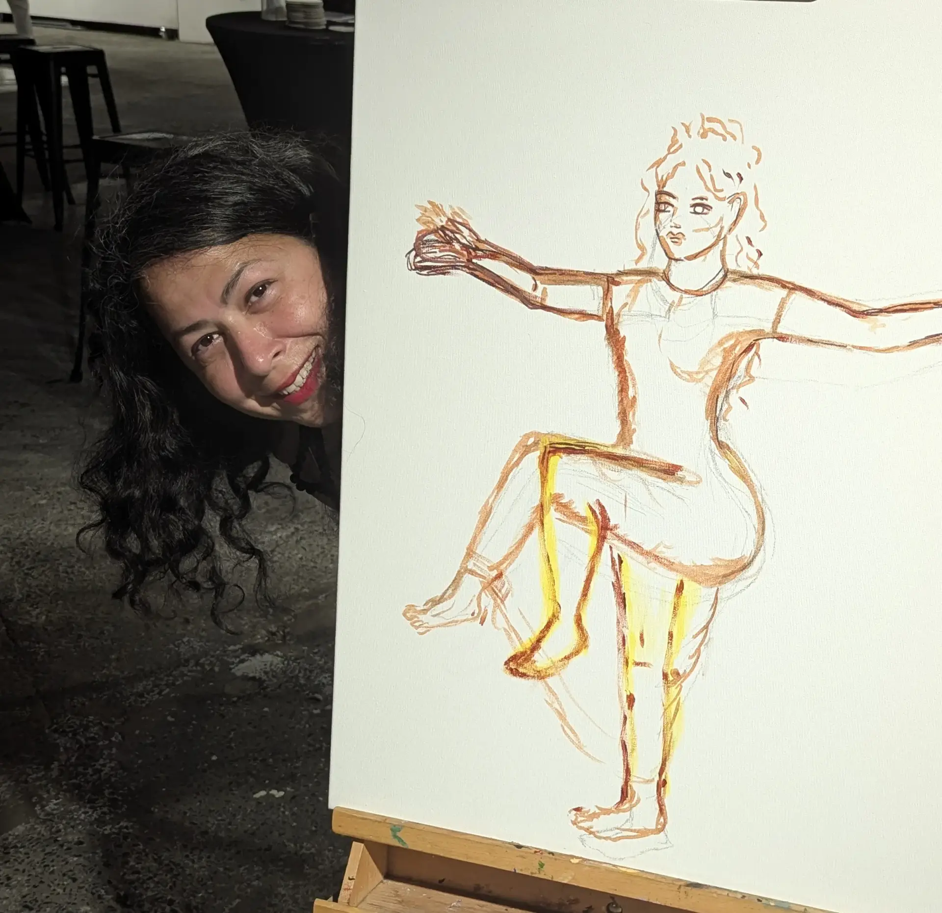 Dilrukshi Mendis looked out from behind a work in progress canvas depicting a drawing of. a woman dancing